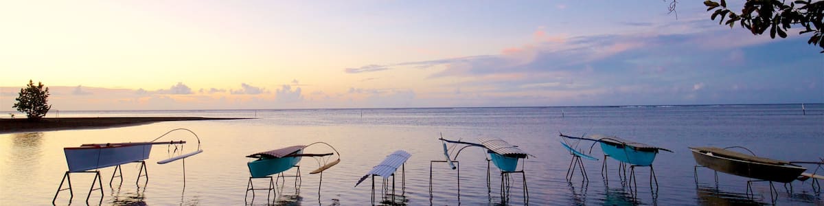 A calm body of water with several boats floating on it, surrounded by a clear sky and a distant shoreline.