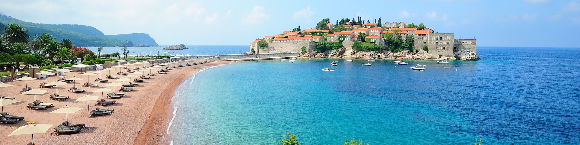 A coastal town with a beach, boats, and a castle-like structure.