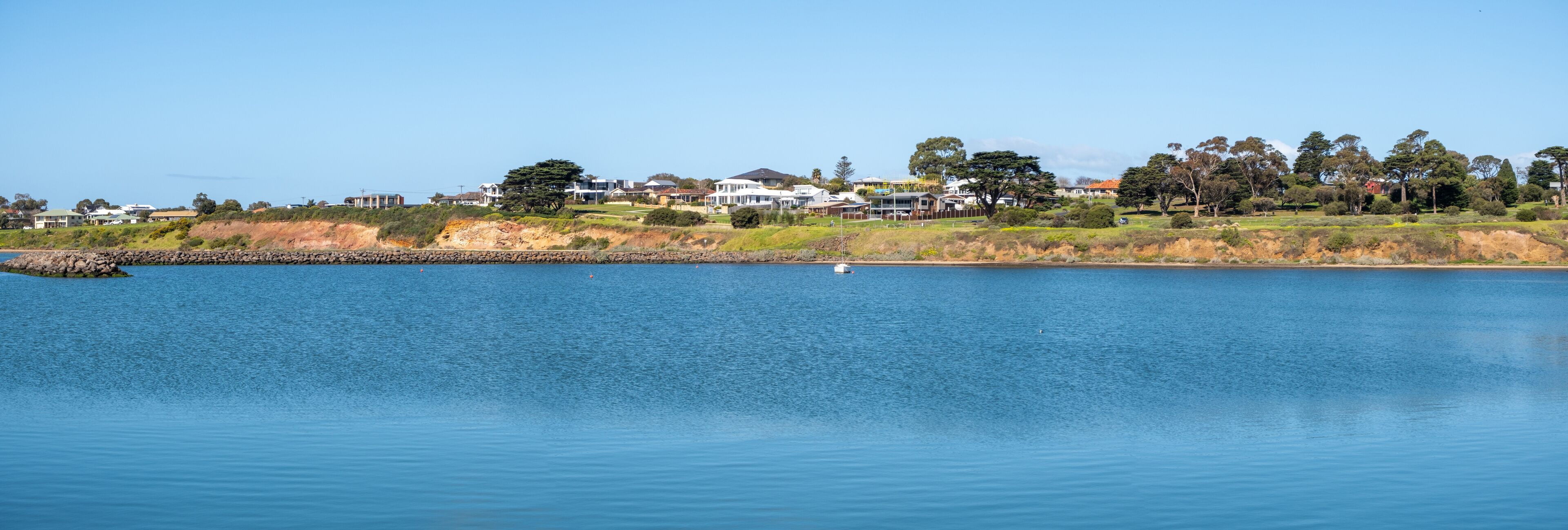 A calm lake with a small boat, surrounded by houses and trees.