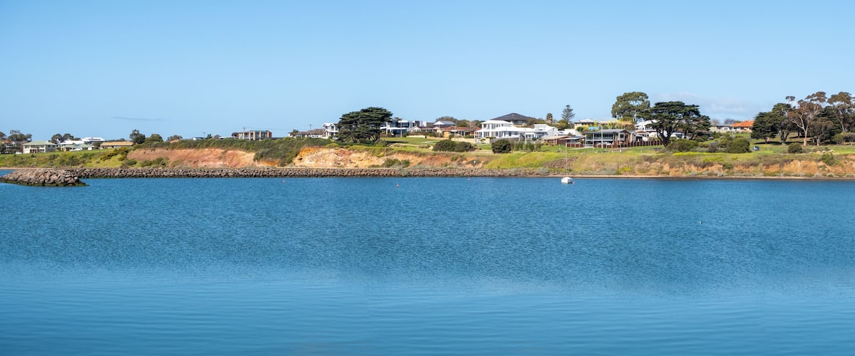 A calm lake with a small boat, surrounded by houses and trees.