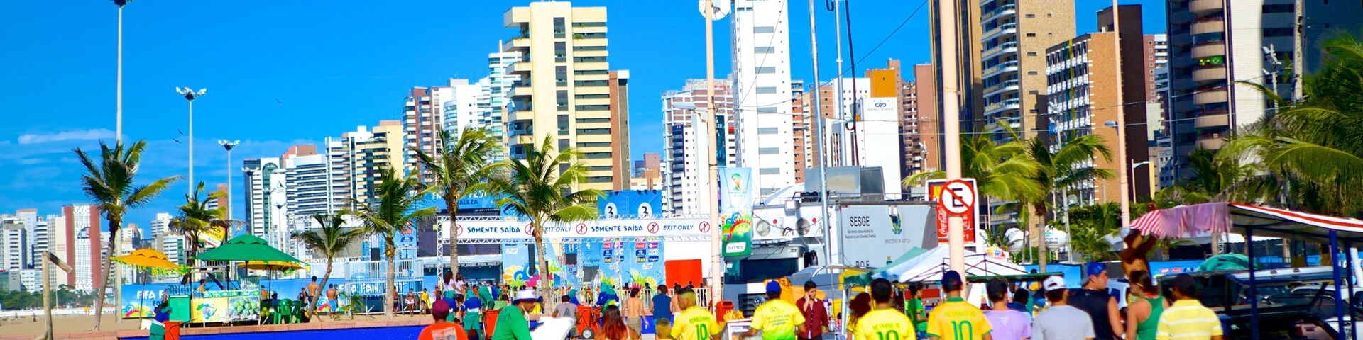 Una calle urbana concurrida, con edificios altos, palmeras y una multitud de gente.