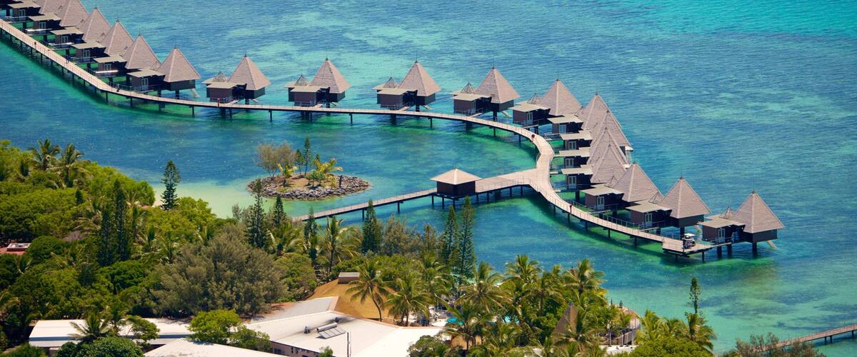 An overwater resort with thatched-roof bungalows connected by walkways.