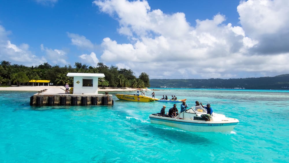 Saipan welches beinhaltet allgemeine Küstenansicht und Bootfahren sowie kleine Menschengruppe