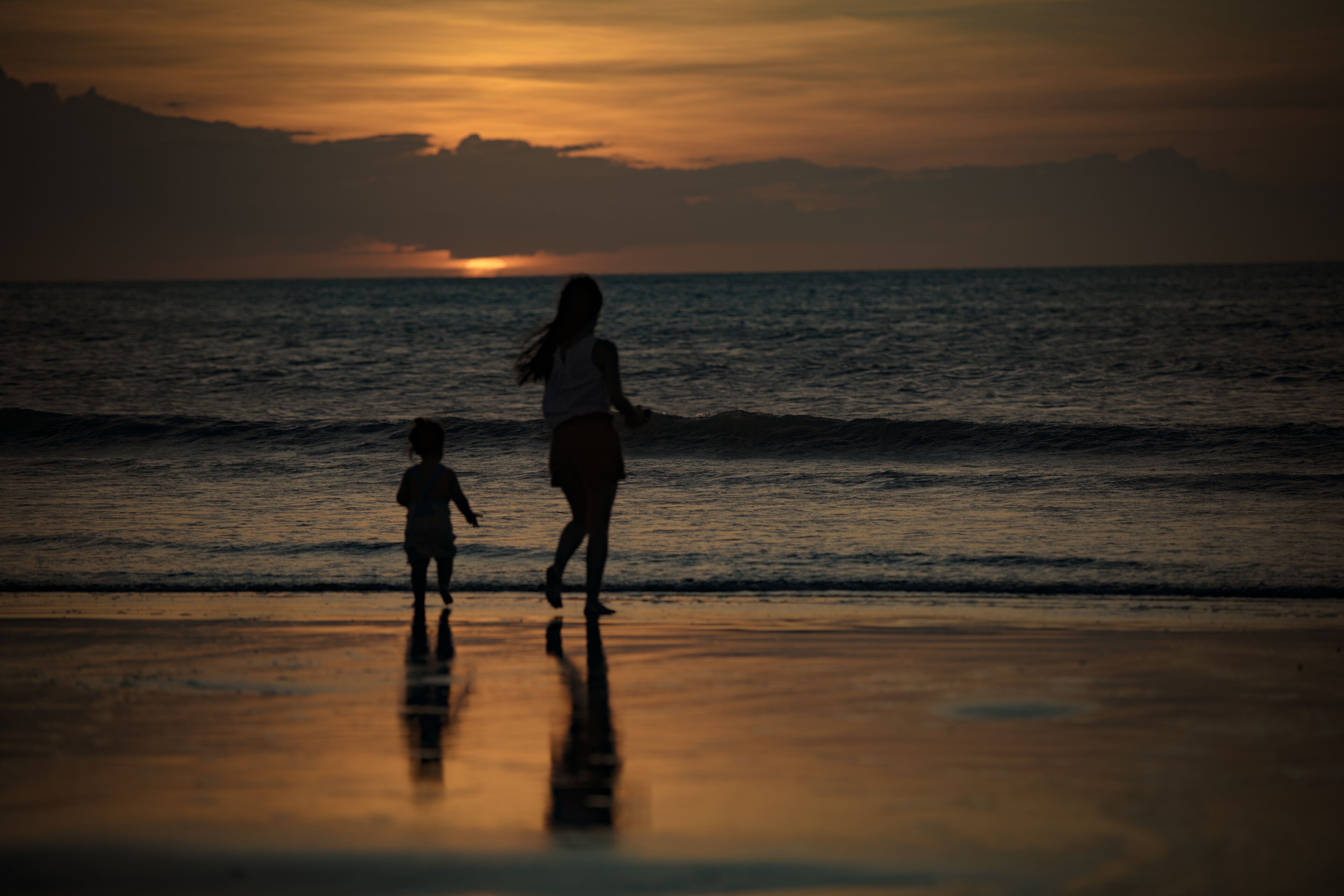 Silhouettes of woman and child at Jericoacoara sunset beach