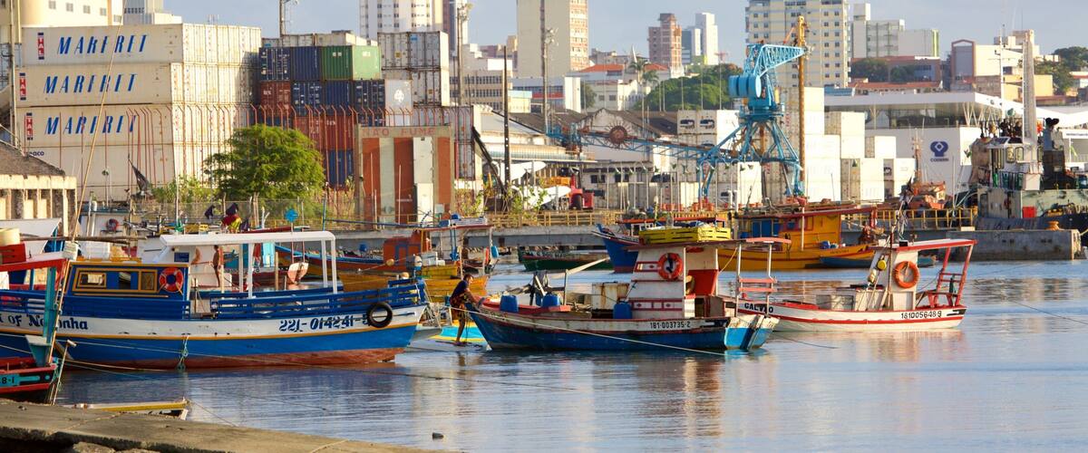 A harbor with various boats docked, surrounded by tall buildings and industrial structures.