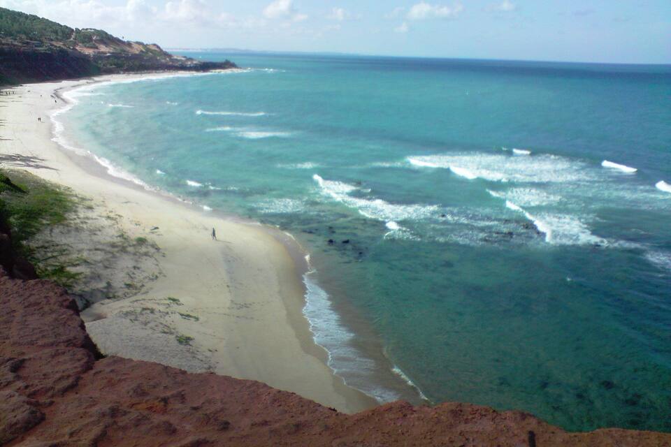 Uma praia costeira com águas turquesa translúcidas e uma faixa de areia.