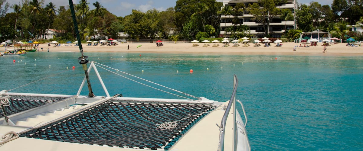 A boat on turquoise water with a beach and palm trees in the background.