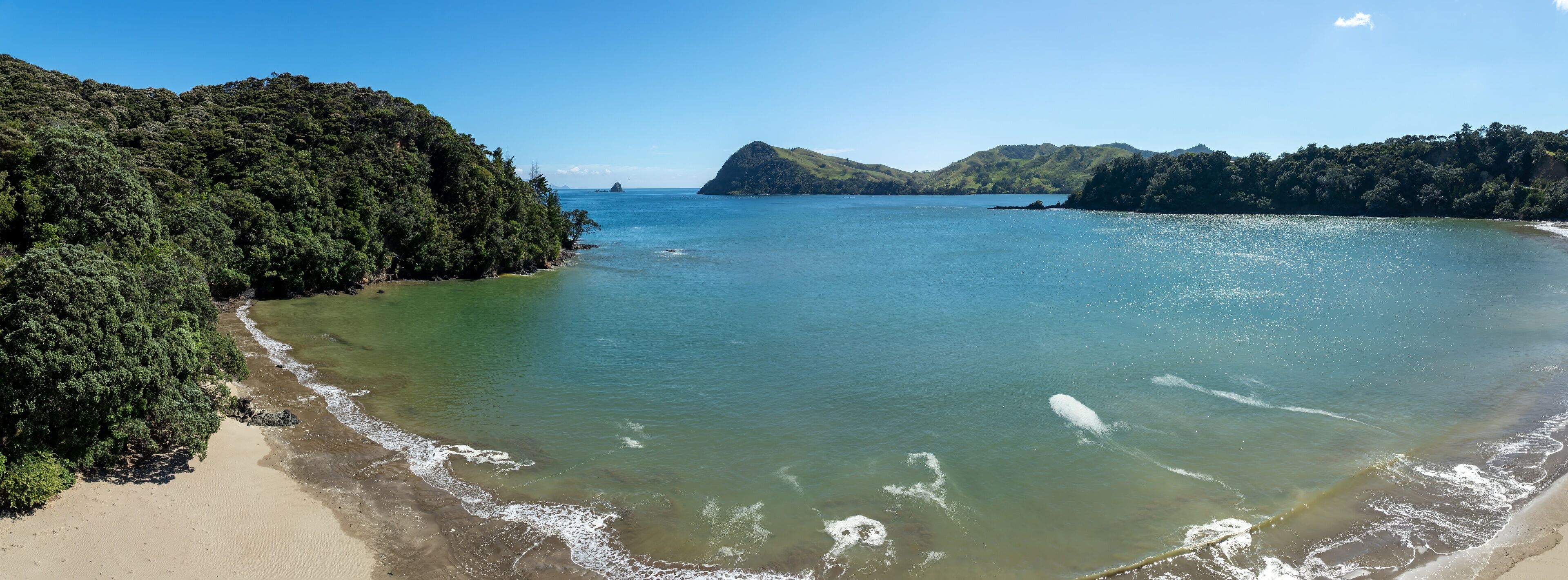 Tranquil bay scene with lush green hills, gentle waves, and pristine beach. Coastal New Zealand beauty. , PORT CHARLES, COROMANDEL PENINSULA, NEW ZEALAND