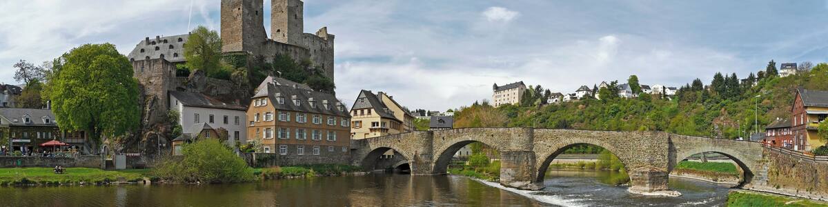 Panorama der hessischen Stadt Runkel. Links die Burg Runkel, Bildmitte die Lahnbrücke, davor das Wehr der Lahn und im Hintergrund die Burg Schadeck.