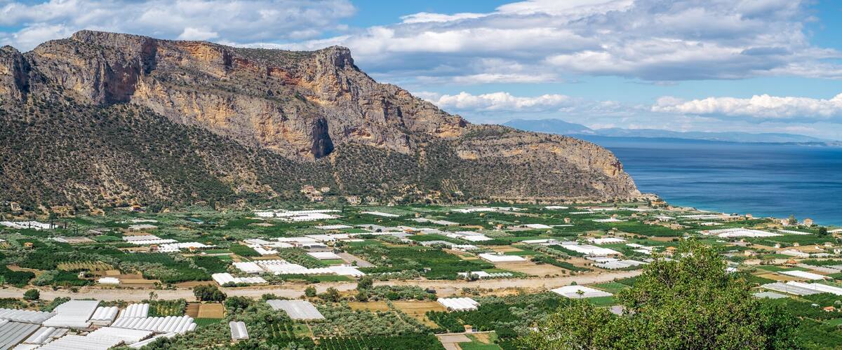 A mountainous landscape with green fields and white buildings.