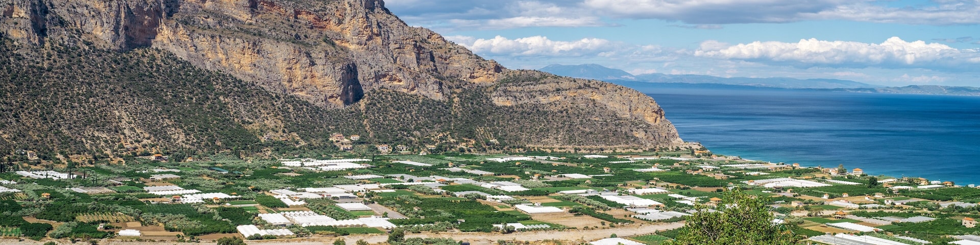 A mountainous landscape with green fields and white buildings.