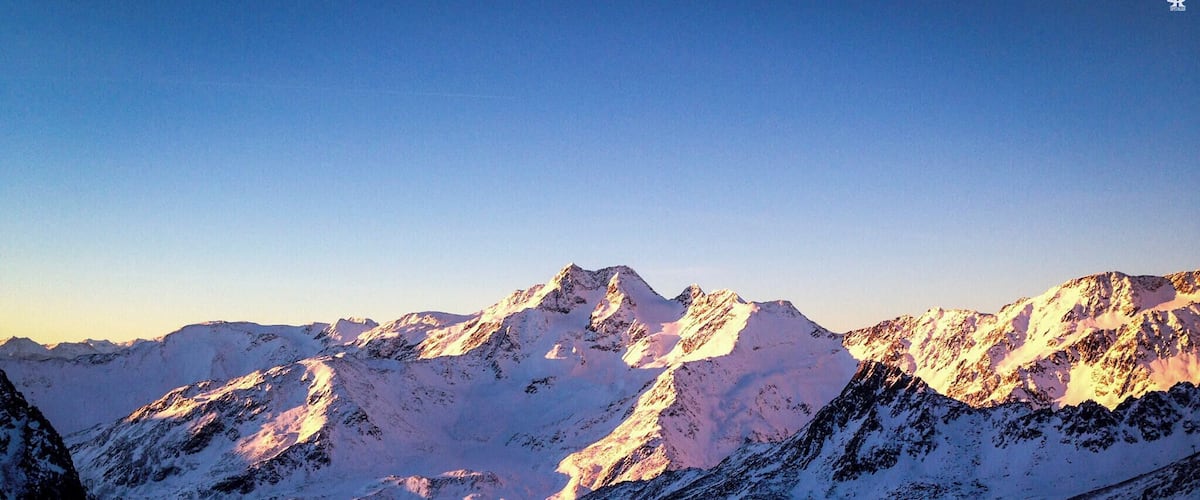 A snow-covered mountain range with sharp peaks and a clear sky.