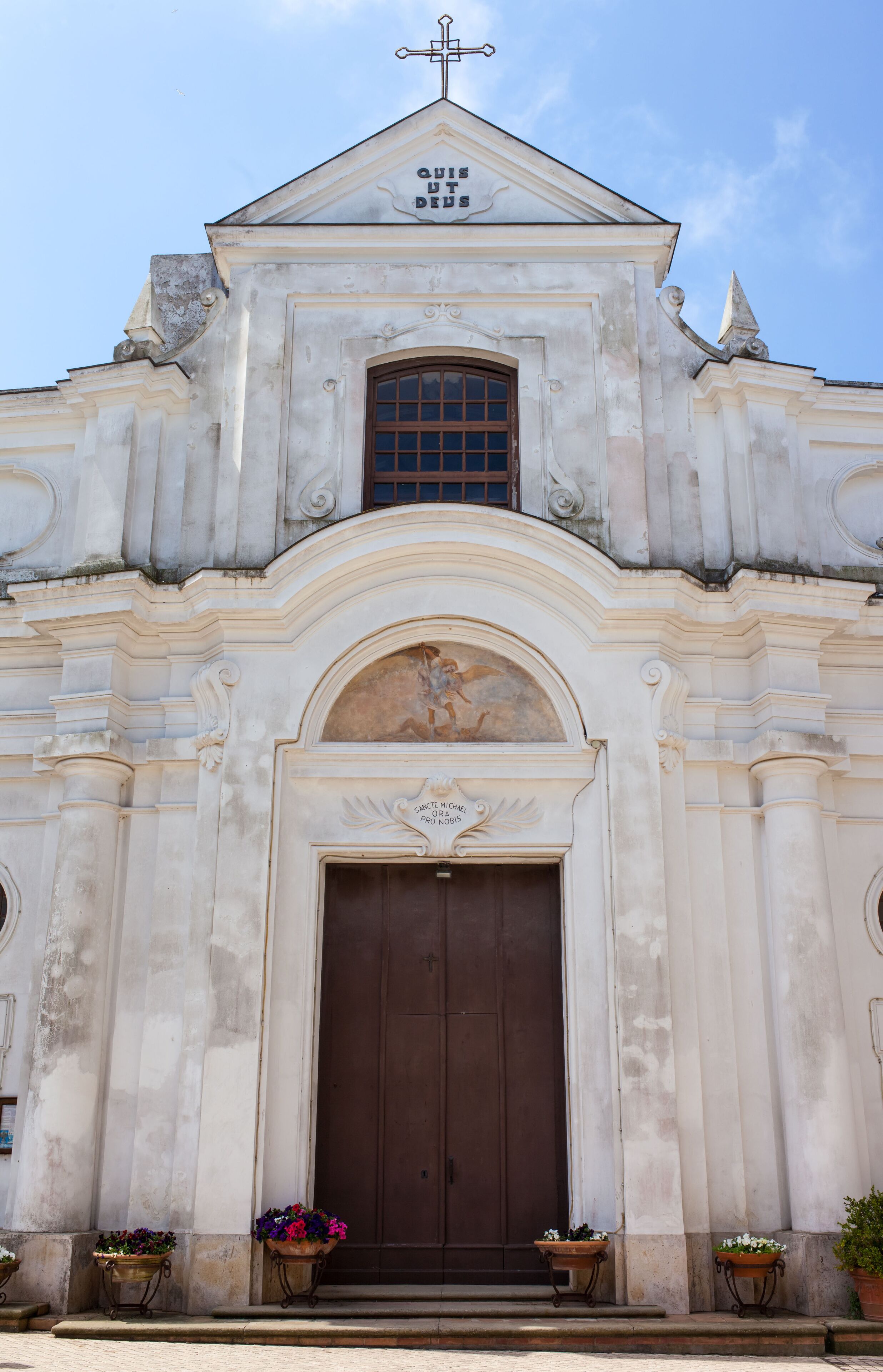A white church with a brown door and a cross on top.