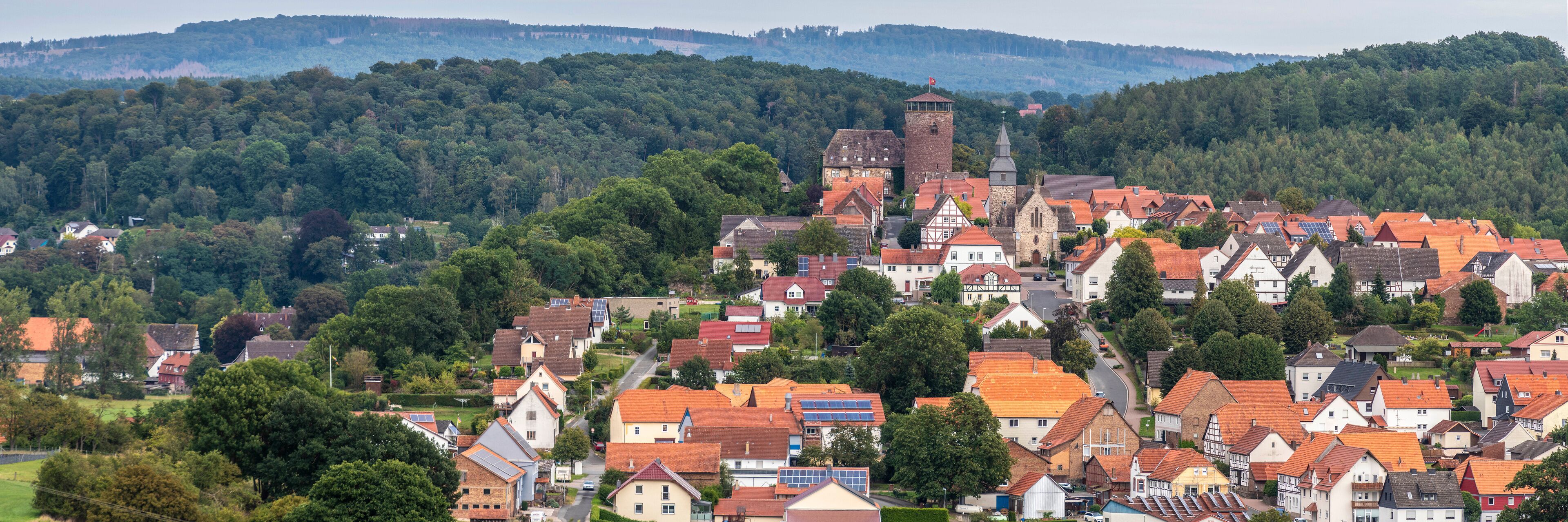A town with traditional houses, a church, and a tower on a hillside.