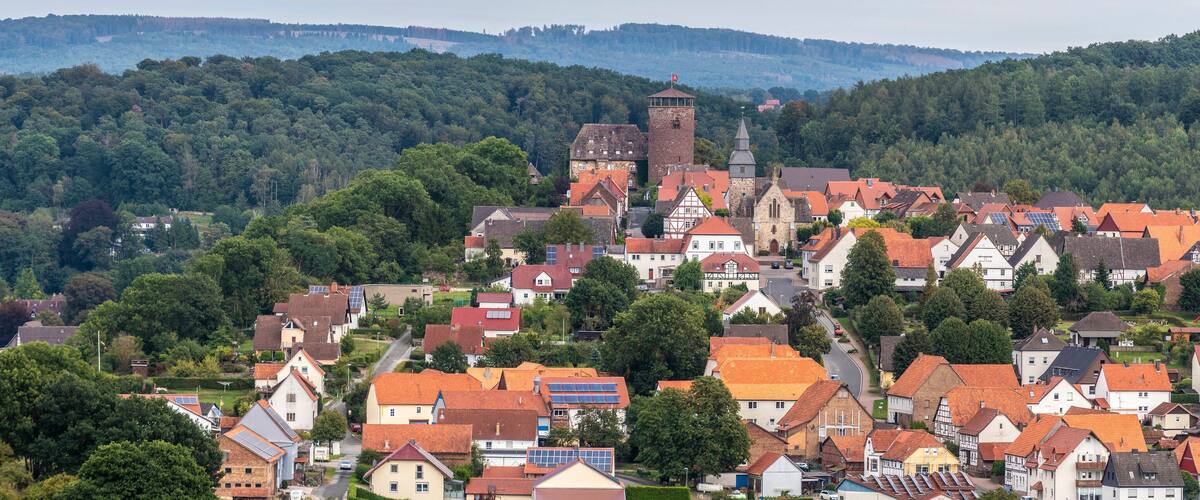 A town with traditional houses, a church, and a tower on a hillside.