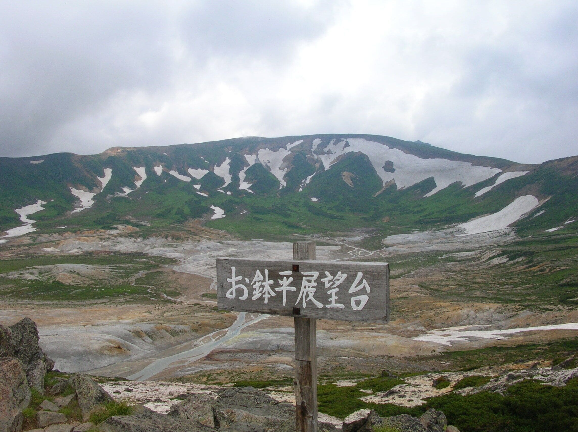 A mountainous landscape with a sign in the foreground.