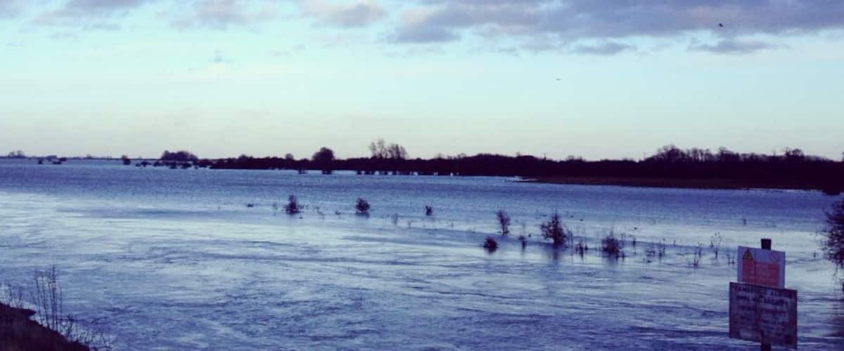 A flooded river with a warning sign.
