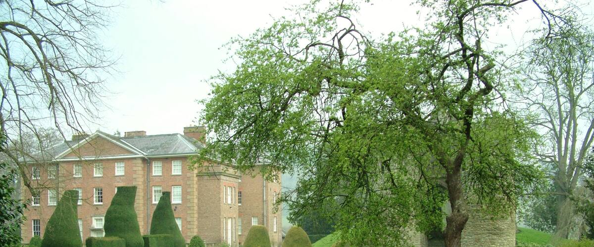 A large brick building with a well-maintained lawn and trimmed hedges.