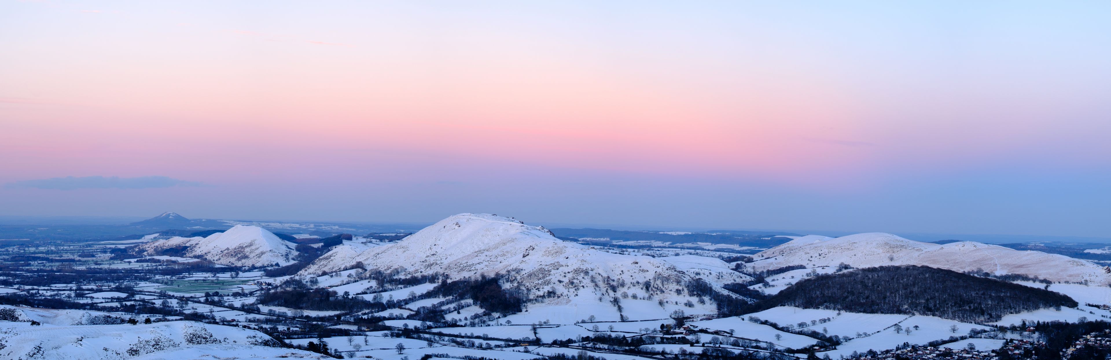Una catena montuosa innevata con un villaggio ai piedi.
