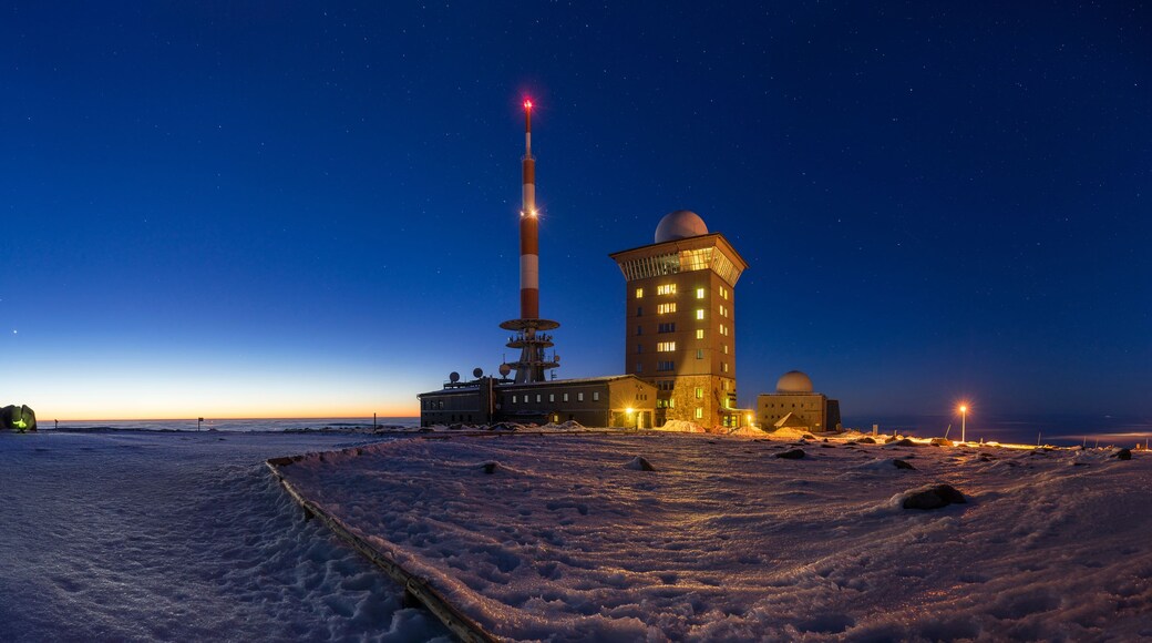 A snowy landscape with a large building, a tall tower, and a telescope.