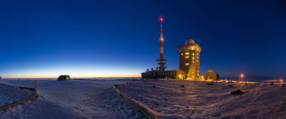 A snowy landscape with a large building, a tall tower, and a telescope.