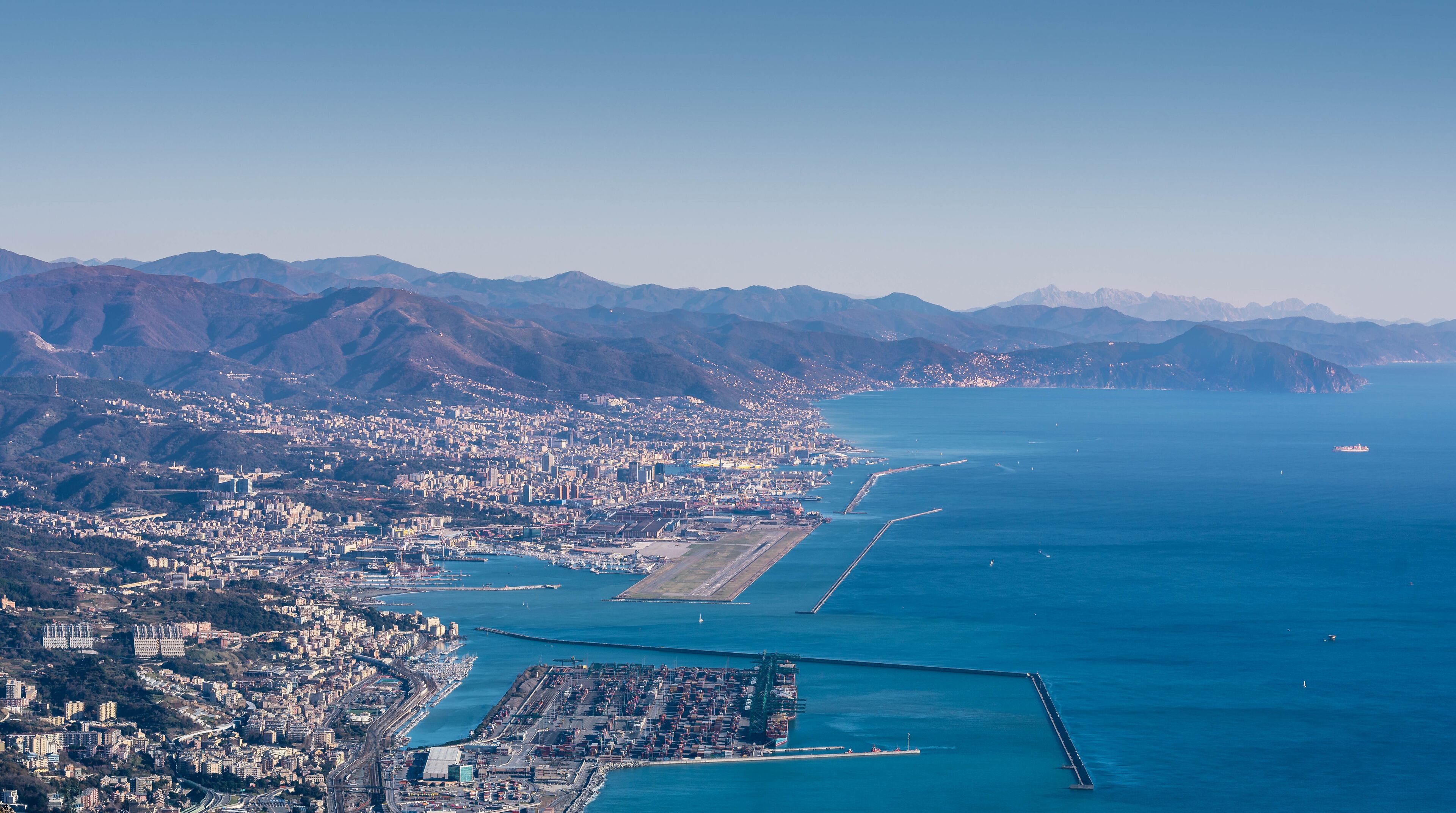 Genoa, Genova, Liguria, Italy: beautiful scenic aerial view of the city, port, dam, sea, Cristoforo Colombo airport runway, and Portofino promontory at sunset