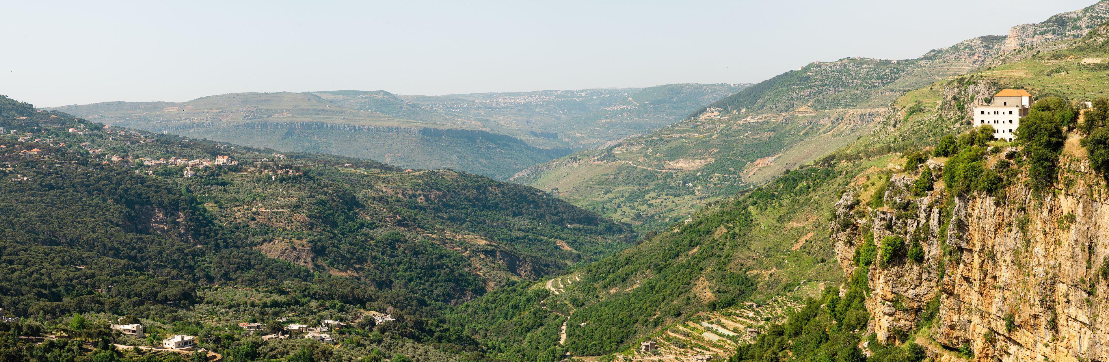 A mountainous landscape with a valley, a village, and a building on a cliff.