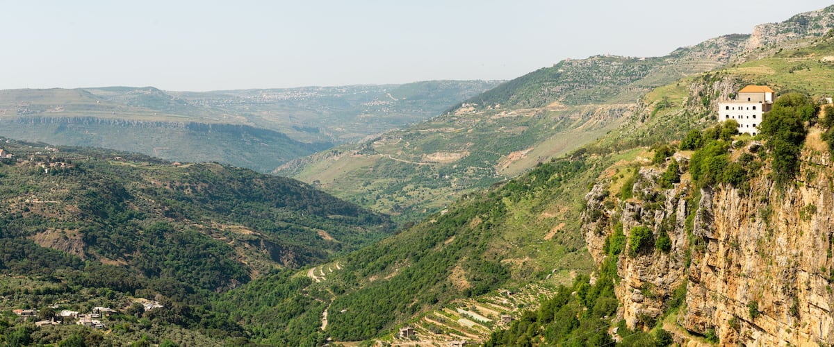 A mountainous landscape with a valley, a village, and a building on a cliff.