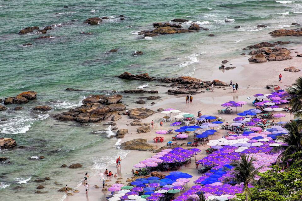Una platja amb roques i persones passejant al llarg de la riba.