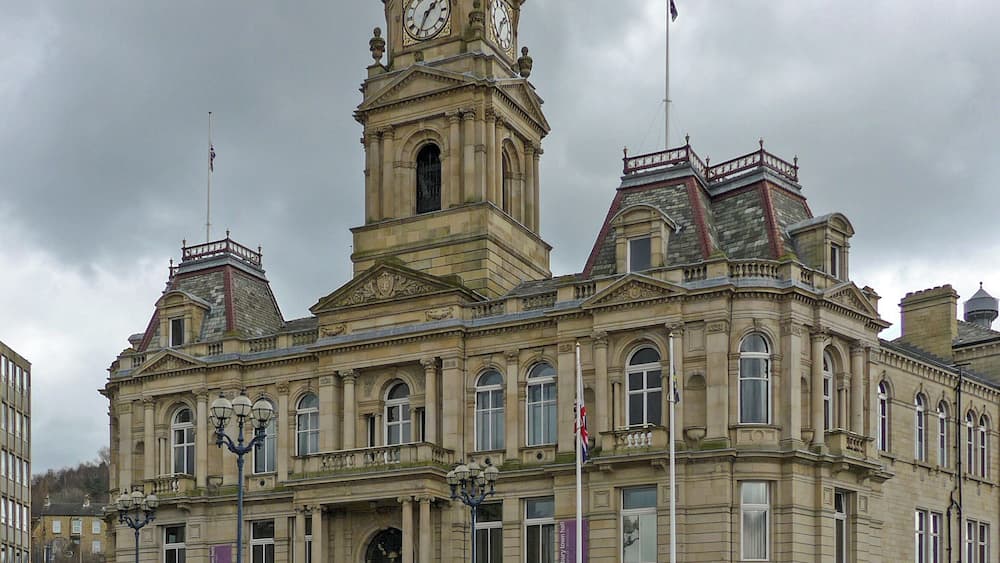 Un bâtiment historique doté d’une tour horlogée, de colonnes et de drapeaux.
