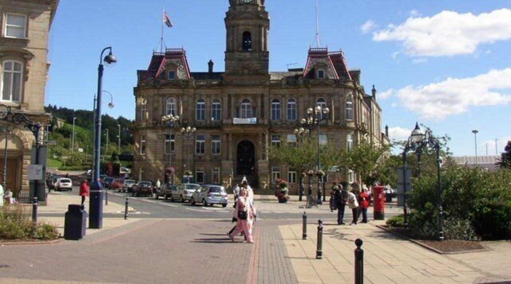 Town Hall, Dewsbury. This Town Hall houses both the council offices and two public halls. It was completed in 1889, and was designed by Holton and Fox, of Dewsbury. Mr Fox also designed Morley Town Hall, and he went on to be mayor of Dewsbury in 1894, just one year after being first elected onto the council. It is not clear on the photo (I should have noticed that the pedestrians were in line with it!) but there is a grand flight of steps up to the main entrance on the first floor. The road on the left side of the building was the main road to Leeds, and the one on the right side to Wakefield, but these have now both been intercepted by the ring road.