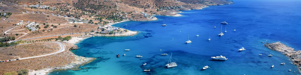A coastal town with a clear blue sea, boats, and a winding road.