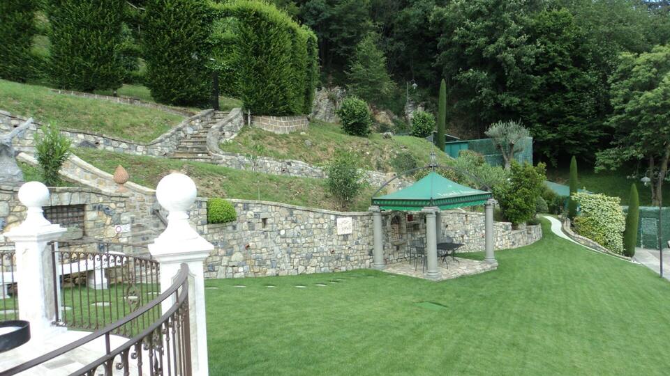 A stone staircase leading up a hill, a green gazebo, and a well-maintained lawn.