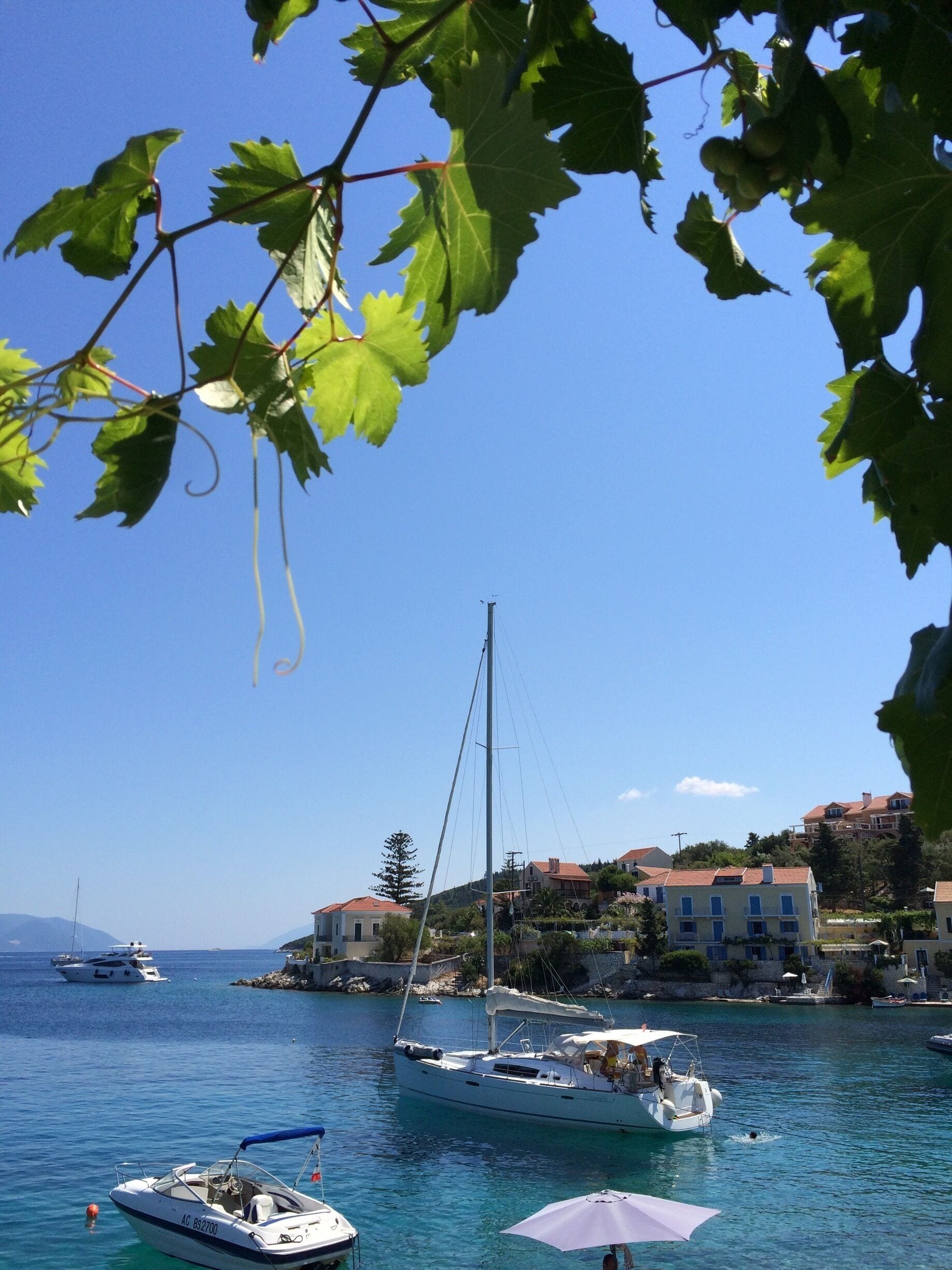 A coastal town with boats on the water, buildings on the shore, and a clear blue sky.