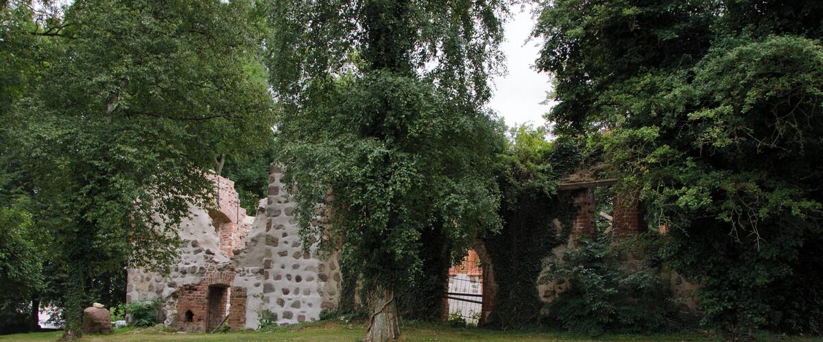A historic stone building surrounded by lush greenery and trees.