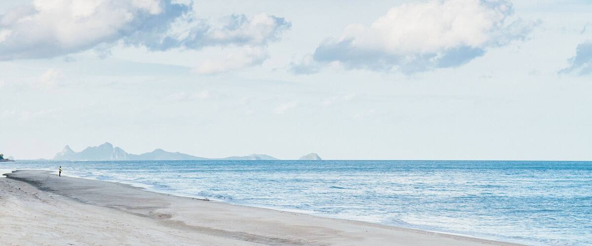 A beach with a clear sky and distant mountains.