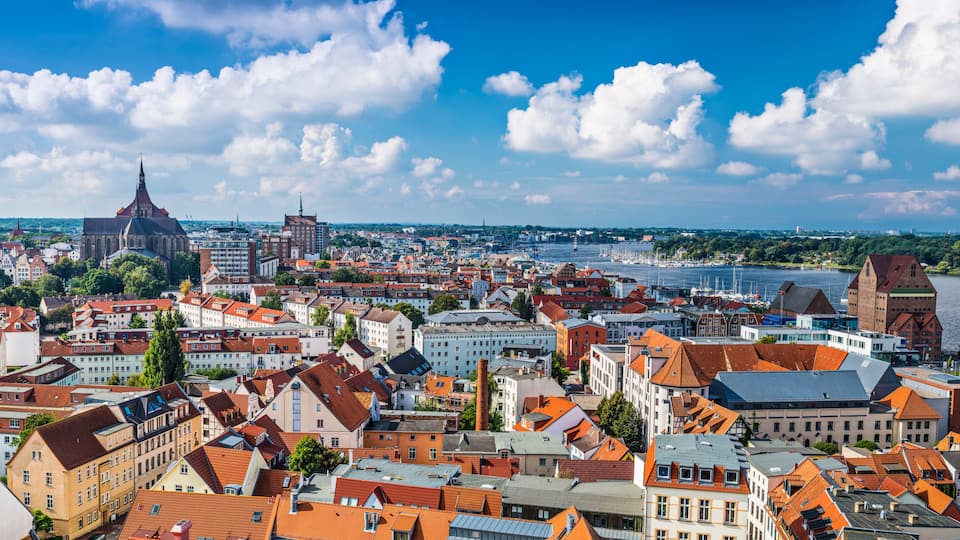 A panoramic view of a city with a river, historic buildings, and a prominent church spire.