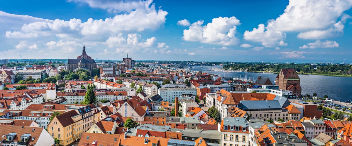 A panoramic view of a city with a river, historic buildings, and a prominent church spire.