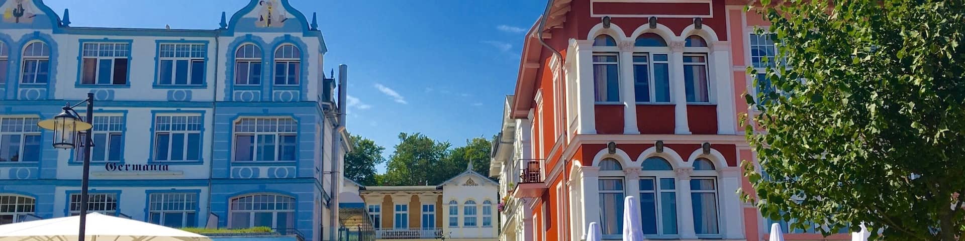 A street with colorful buildings, outdoor seating, and a clear blue sky.