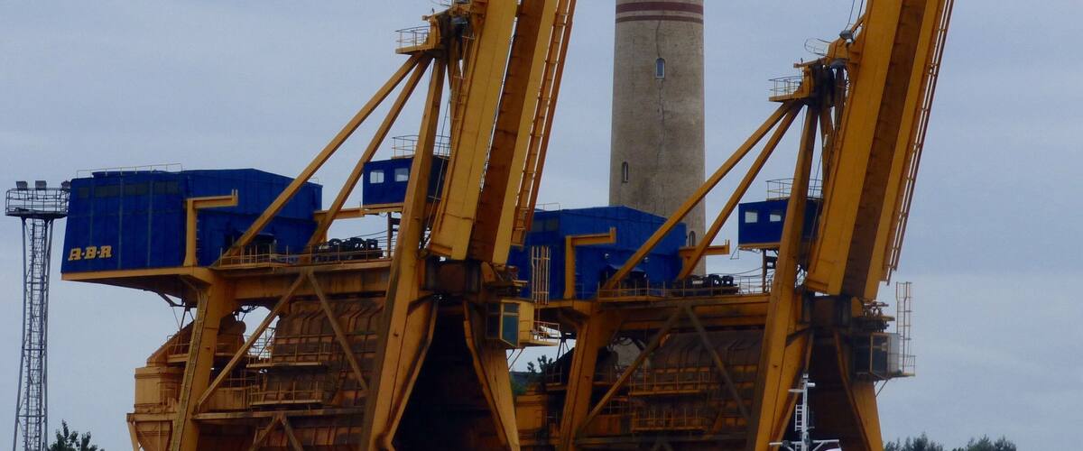 A construction site with large yellow cranes and a tall tower in the background.