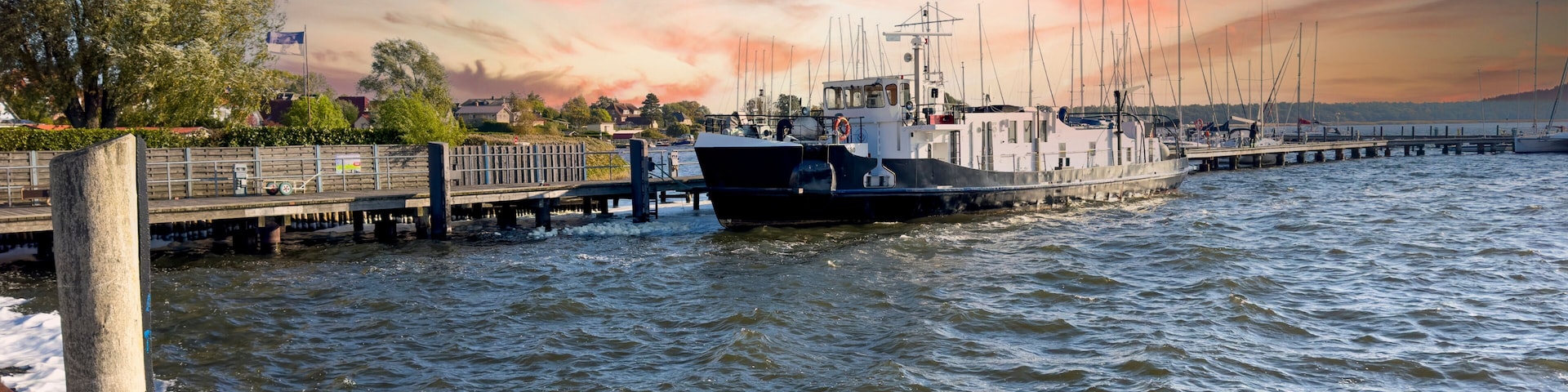 Un puerto con un barco amarrado, un muelle que se adentra en el agua y un cielo al atardecer.