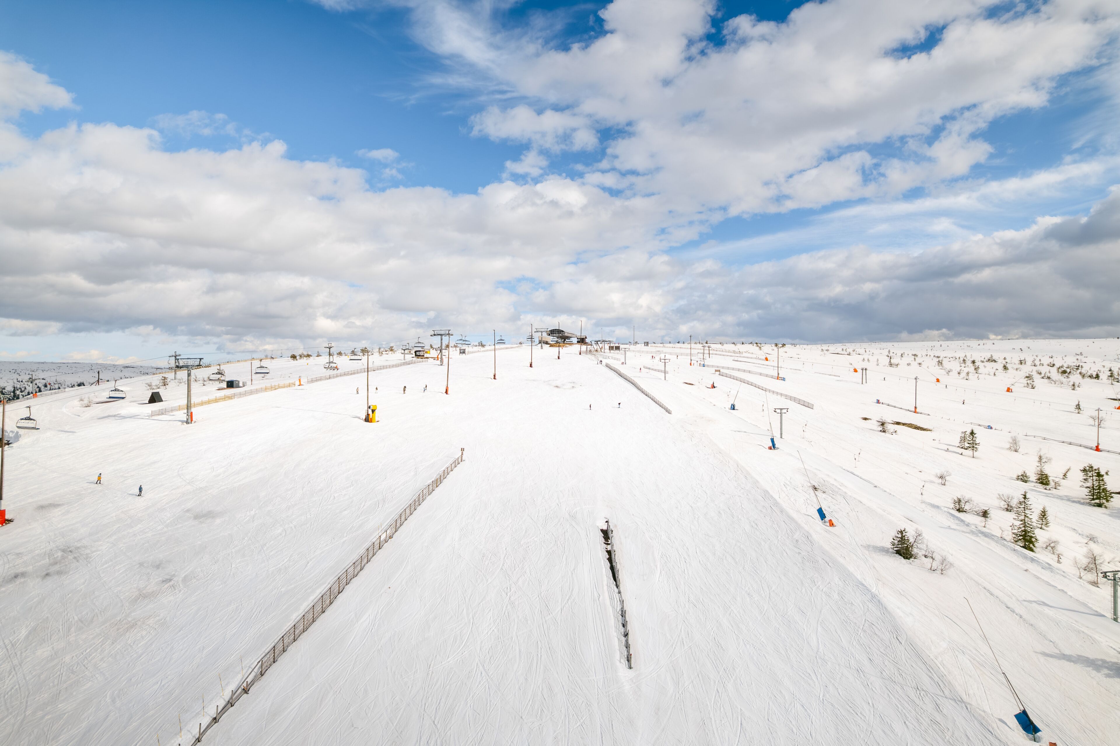 Una pista de esquí nevada con remontes, árboles y un cielo despejado.