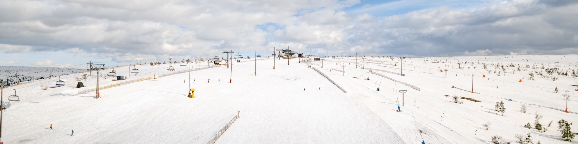 Una pista de esquí nevada con remontes, árboles y un cielo despejado.