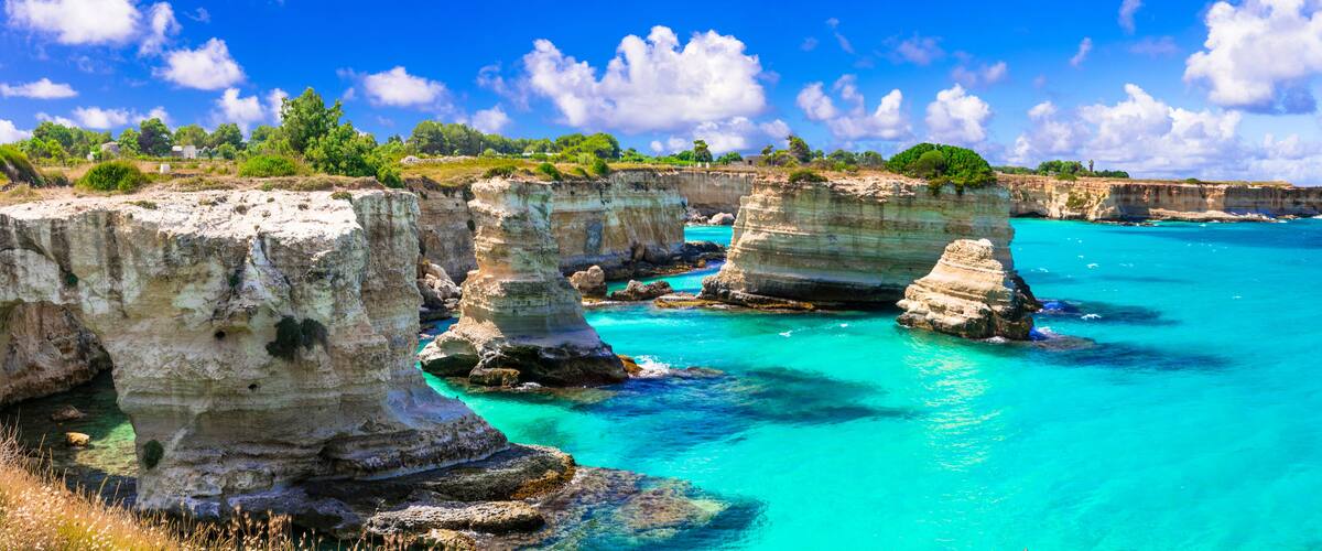 A coastal landscape with prominent white rock formations and turquoise waters.