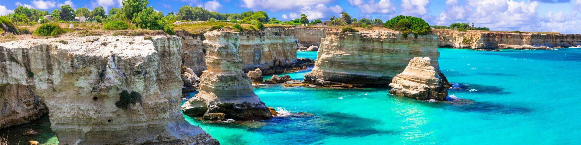 A coastal landscape with prominent white rock formations and turquoise waters.