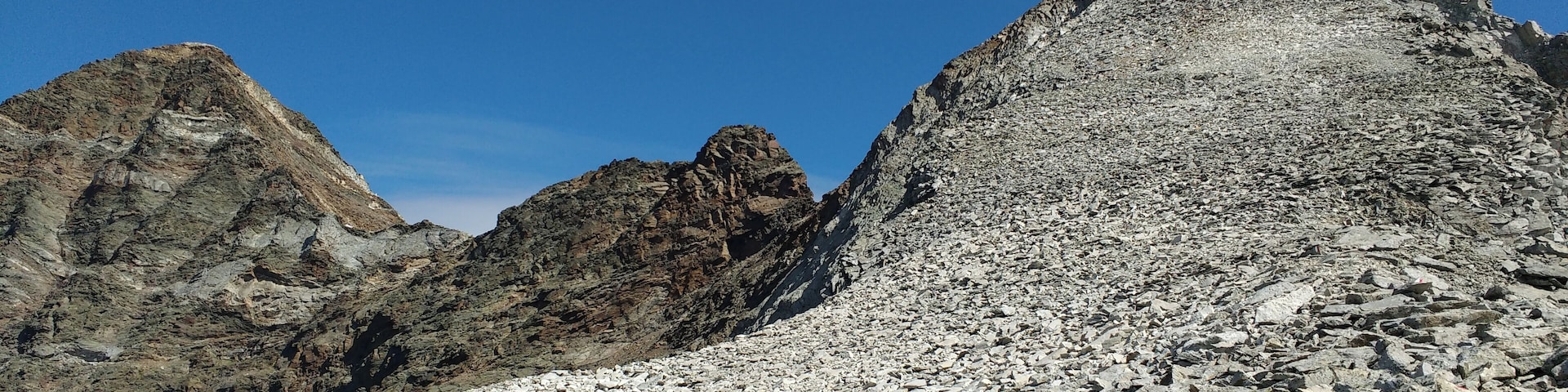 A rocky mountain landscape with rugged peaks and a clear blue sky.