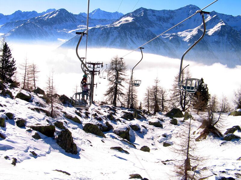 Montanha coberta de neve com teleféricos e céu claro.