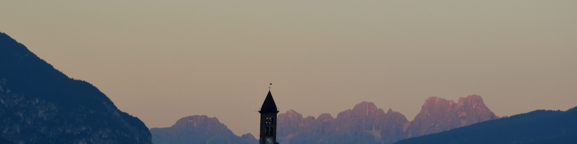 A church with a bell tower surrounded by mountains.