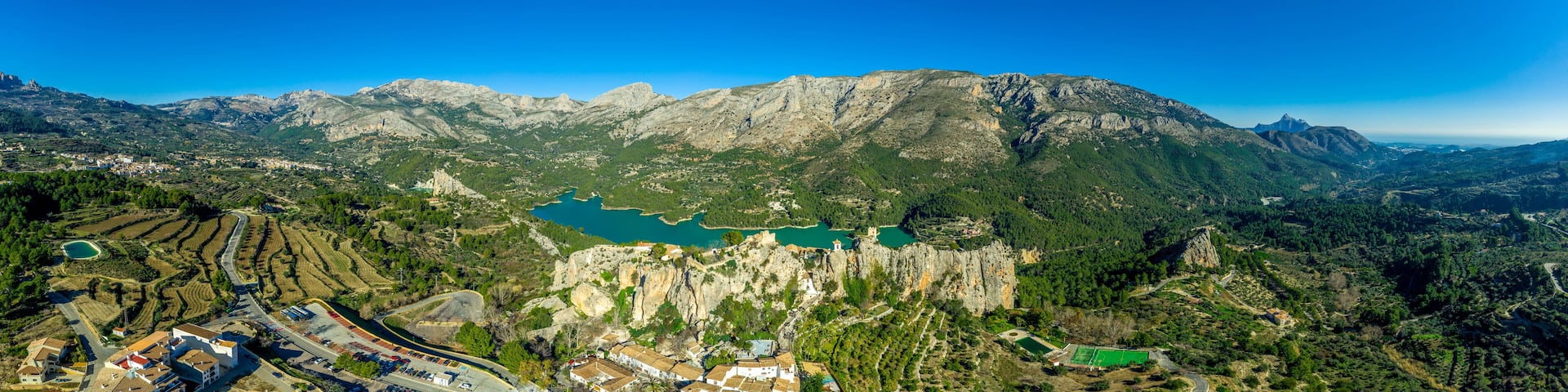 Panoramic view of popular Spanish vacation destination El Castell de Guadalest above a beautiful water reservoir with 2 castles and fortified enclave