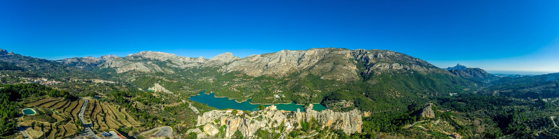 Panoramic view of popular Spanish vacation destination El Castell de Guadalest above a beautiful water reservoir with 2 castles and fortified enclave